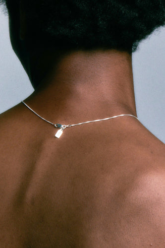 Box Chain in 925 silver at the nape of the neck, clasp and tag resting between the shoulders.