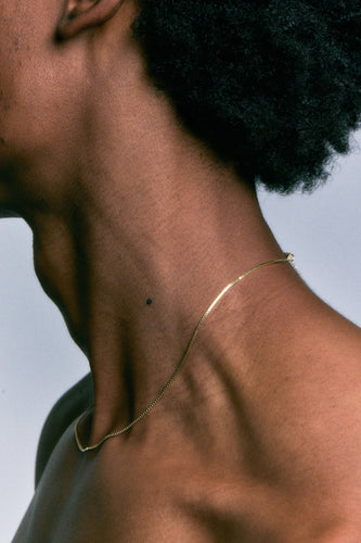 Box Chain in 14k gold worn along the collarbone, close side view.