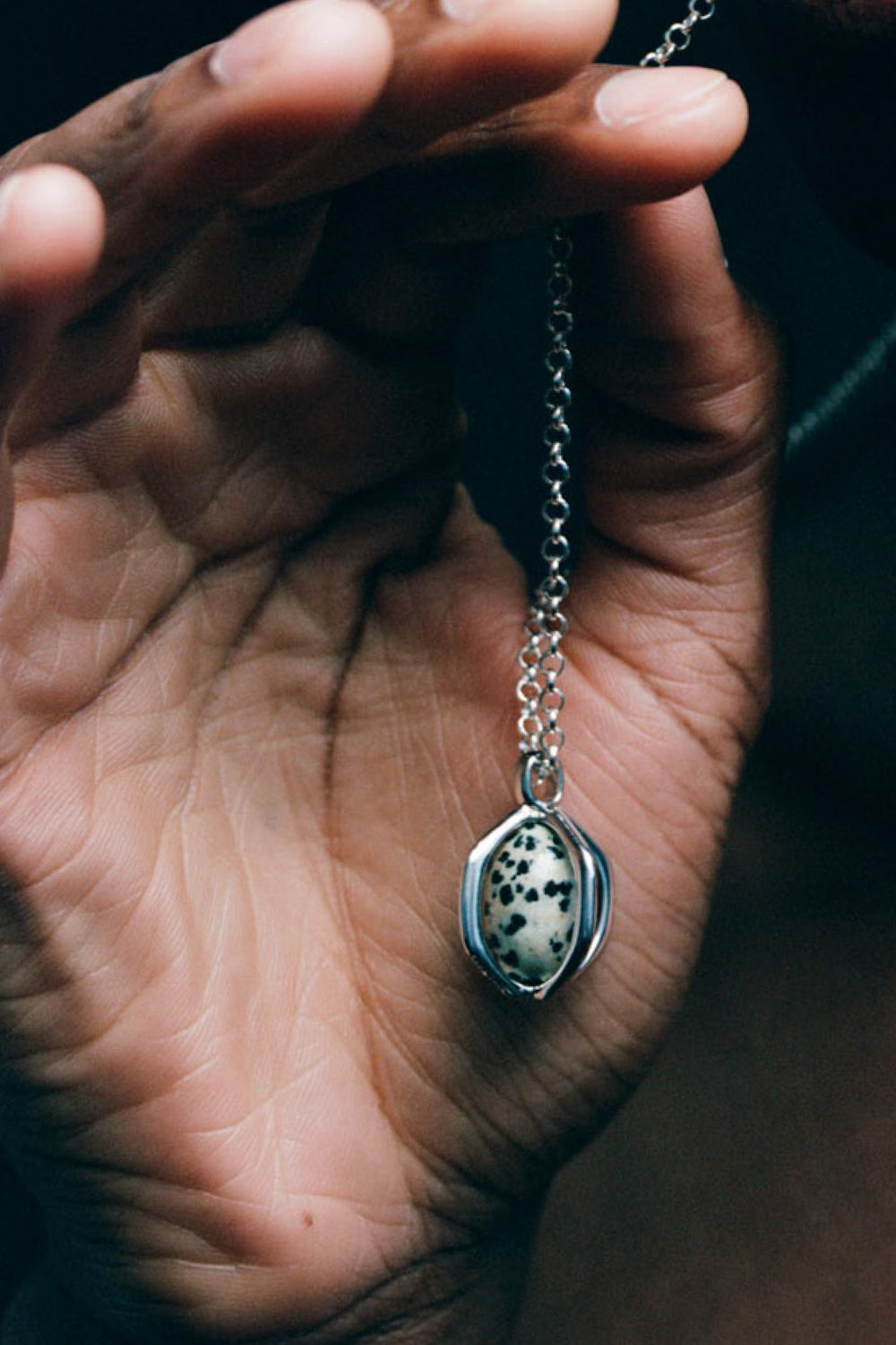 Quail Egg Necklace in 925 silver, the speckled dalmatian jasper pendant held in an open palm.