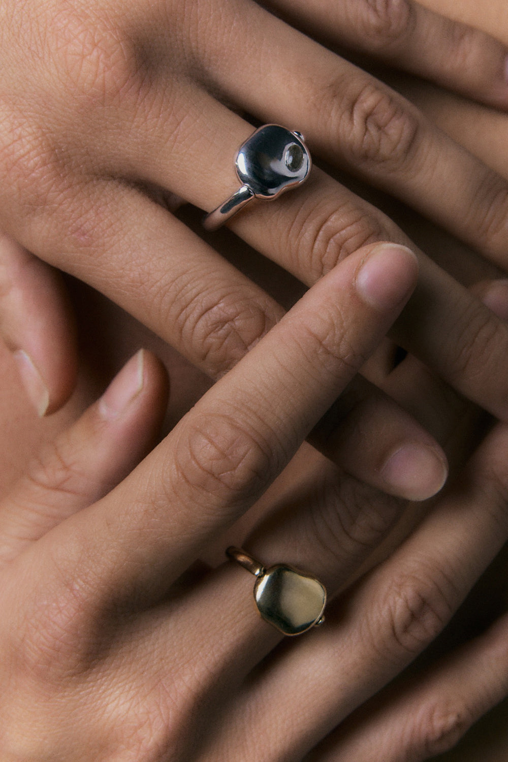 FF Swivel Ring shown in 925 silver and 14k gold on two hands, close view of the pebble face.