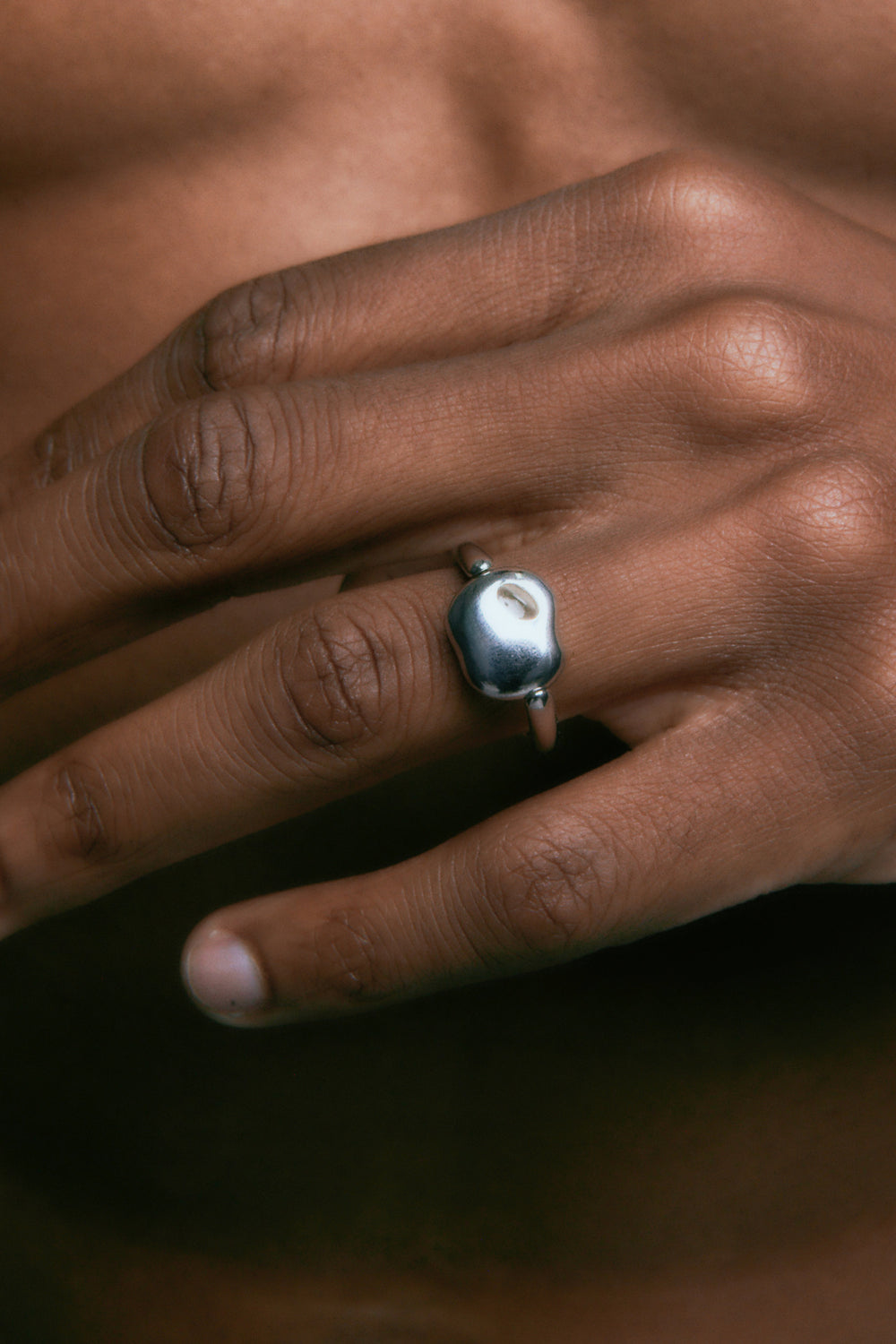 FF Swivel Ring in 925 silver, a smooth pebble face, worn on the ring finger.