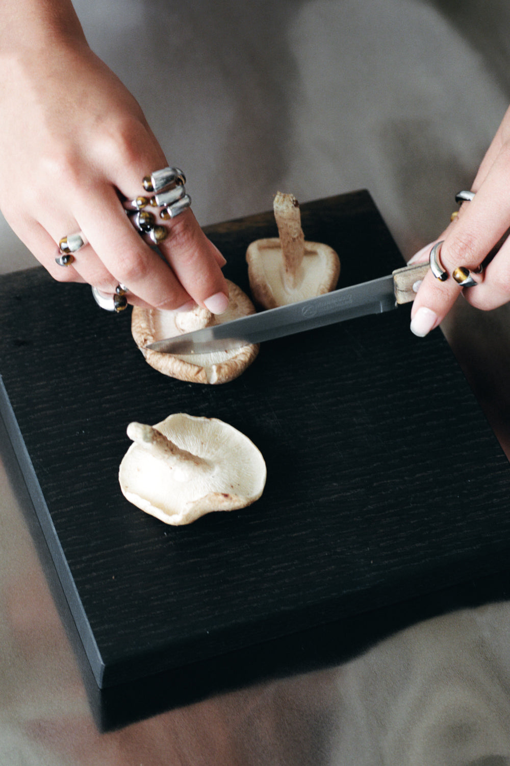 Mushroom Ring in 925 silver worn while slicing shiitake on a black board.