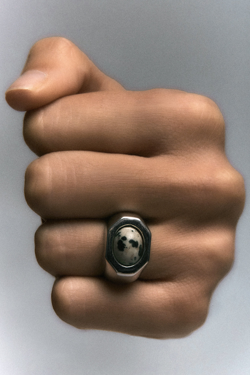 Quail Egg Ring in 925 silver, speckled dalmatian jasper in a faceted bezel, on a closed hand.