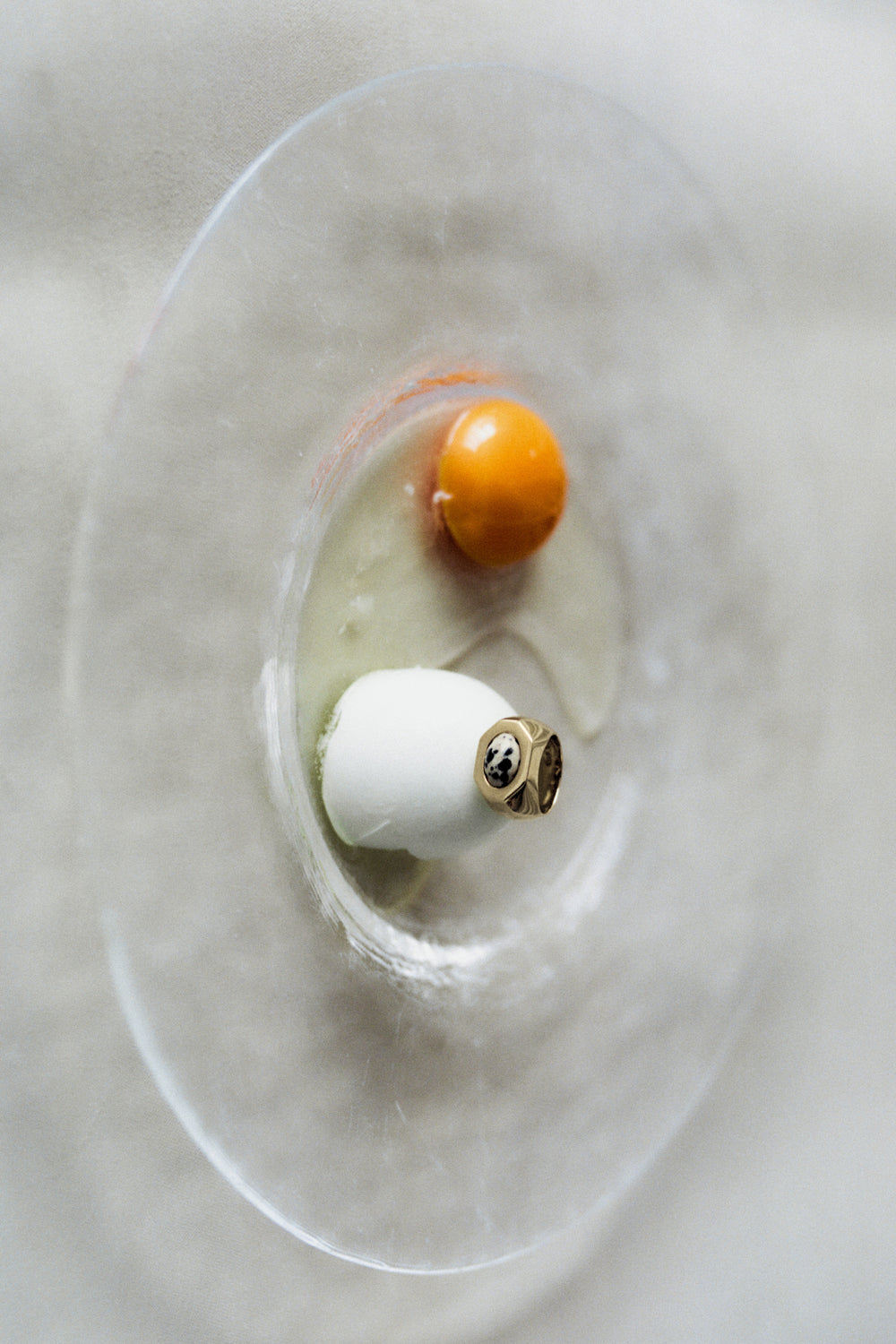 Quail Egg Ring in 14k gold resting on an eggshell beside a yolk, shot from above.